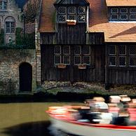 Toeristen in bootje en houten achtergevel langs de Dijver, één van de Brugse reien, Brugge, België
